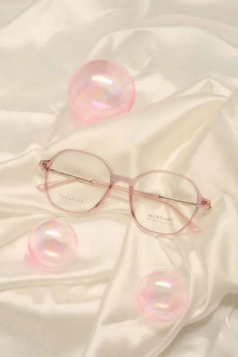 กรอบแว่นสายตา JILL STUART วางบนผ้าไหมสีครีม