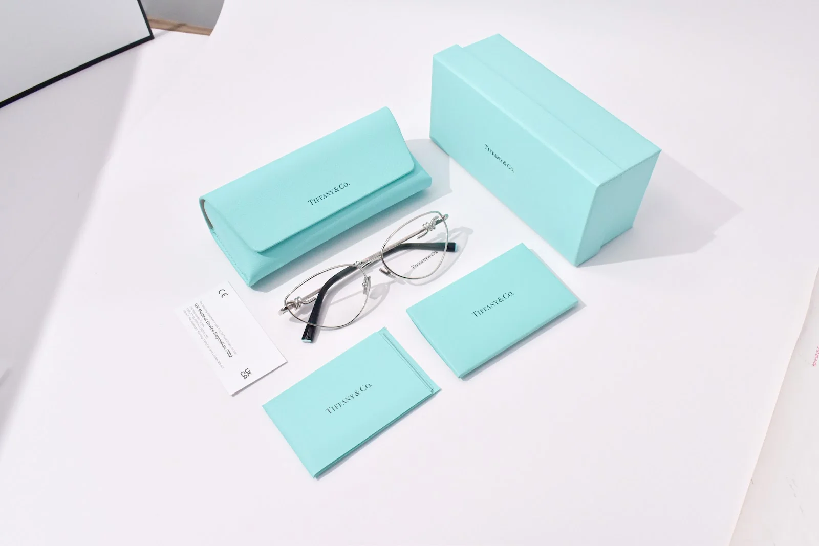 กรอบแว่นโลหะ Tiffany & Co. วางพร้อมกล่องและเคสสีฟ้า