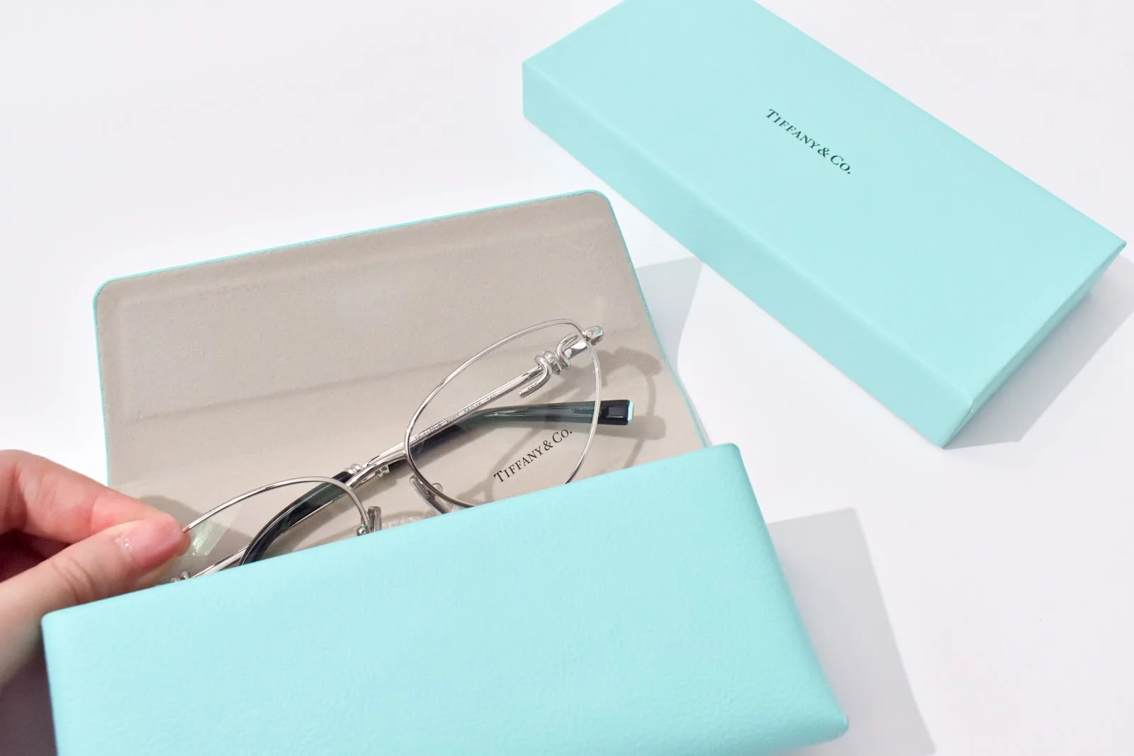 มือที่ถือเคสแว่นสีฟ้าของ Tiffany & Co.